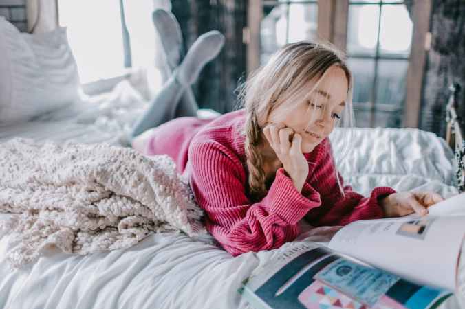 woman reading book on bed