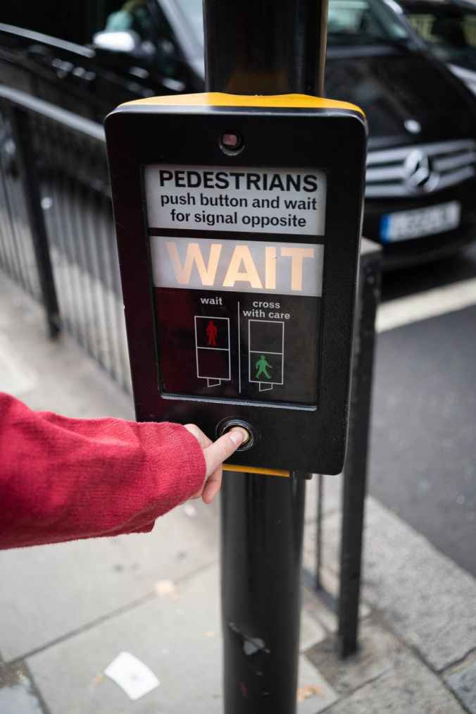photo of person pressing the button of pedestrian box